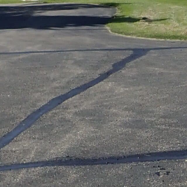 Fresh crack sealant on asphalt ahead of a sealcoat