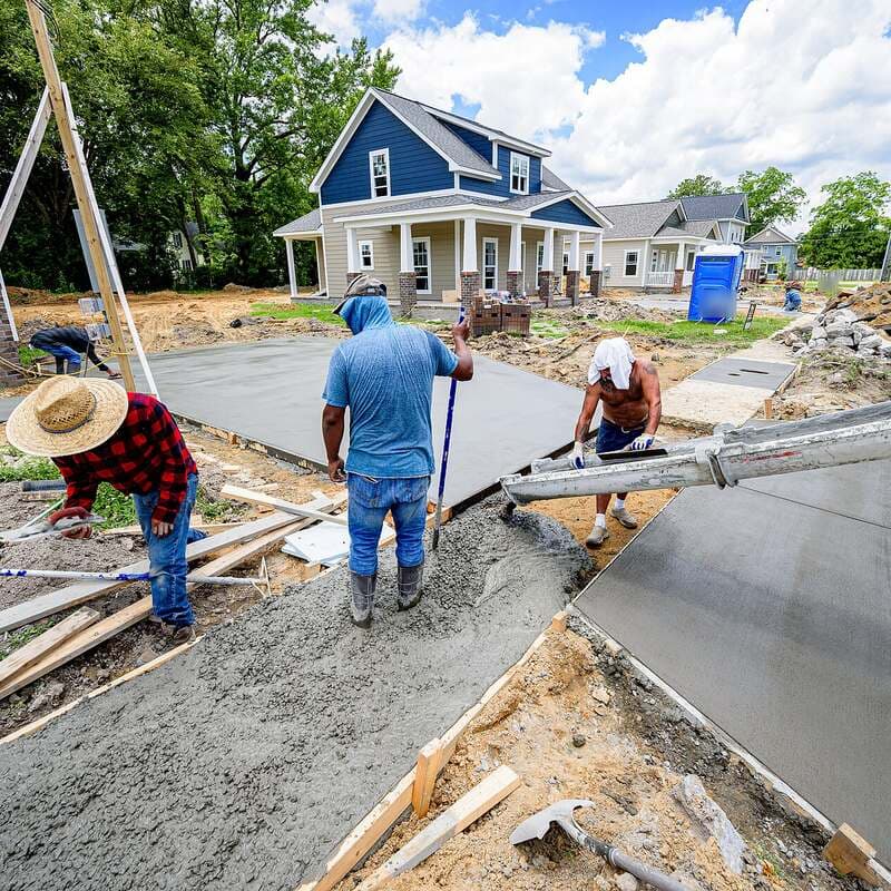 Ready-mix concrete pouring from a truck chute into the forms of a residential driveway