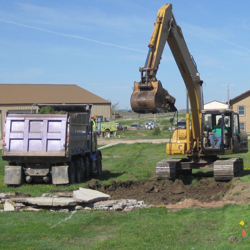 An excavator loads soil into a dump truck on a job site