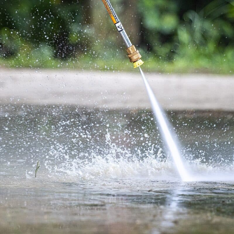 Pressure washing wand rinsing concrete flatwork