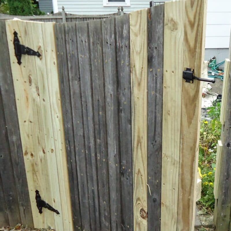 A wood gate rehung on new hinges, seen from the driveway