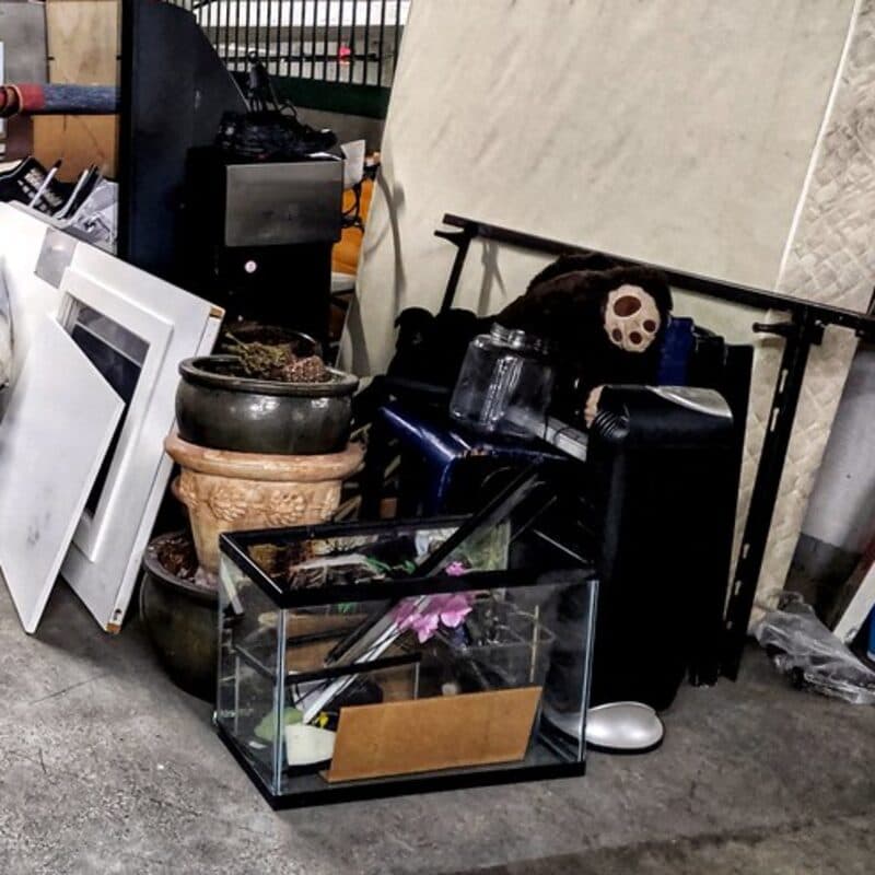 Framed pictures, planters, a glass tank and a mattress staged on a concrete floor, ready to load