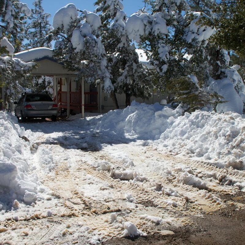 A residential driveway freshly plowed, with snowbanks pushed up along both sides